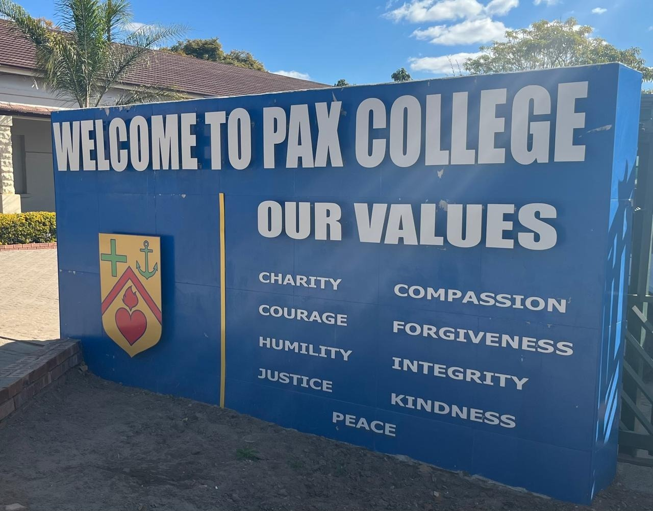 Pax College blue welcome wall with 3D lettering, school crest and values panel